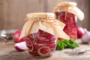 Jars of pickled onions on wooden table