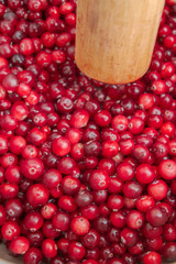 Crush the red cranberry berries with a wooden rolling pin