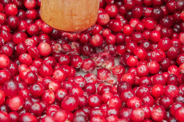 Crush the red cranberry berries with a wooden rolling pin