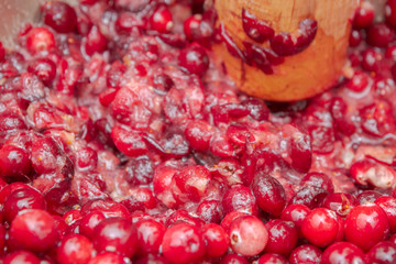 Crush the red cranberry berries with a wooden rolling pin