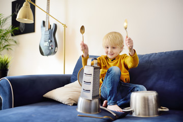 Mischievous preschooler boy play the music using kitchen tools and utensils. Funny drum part from...