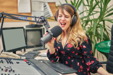 young woman dj works in a broadcasting studio