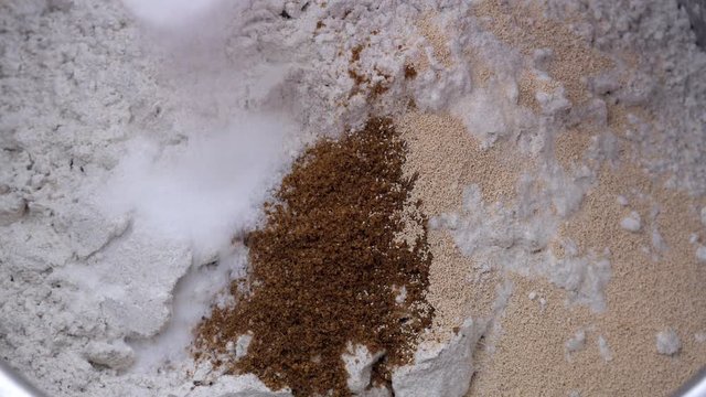 Preparation of homemade bread - adding salt to the flour with dried yeast and ground cumin