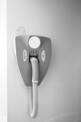 Black and white image of hairdryer hanged on the wall of bathroom in modern hotel with power plug for the razor machine - black and white image.