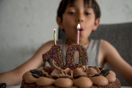 ni&ntilde;o celebrando el cumplea&ntilde;os numero 10 con pastel y velas de aniversario, soplando al pastel