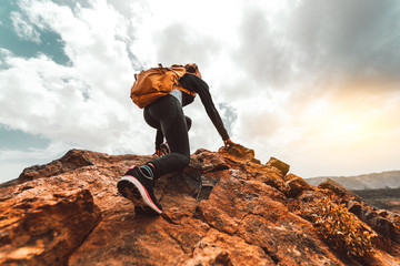 Success woman hiker hiking on sunrise mountain peak - Young woman with backpack rise to the mountain top. Discovery Travel Destination Concept - obrazy, fototapety, plakaty