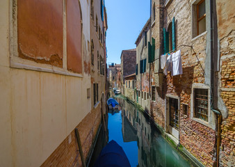 Fototapeta na wymiar Narrow canal in Venice, Italy, with boats and historic houses, in a beautiful sunny day.