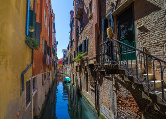 Narrow canal in Venice, Italy, with boats and historic houses, in a beautiful sunny day.