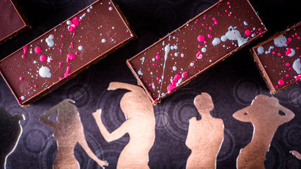 Chocolate brownies with a dark chocolate top set a background of female forms in gold