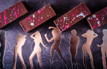 Chocolate brownies with a dark chocolate top set a background of female forms in gold