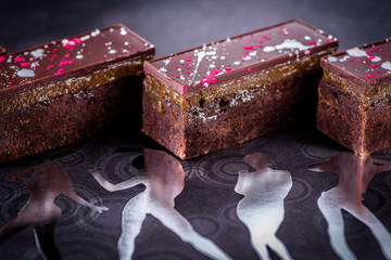 Chocolate brownies with a dark chocolate top set a background of female forms in silver