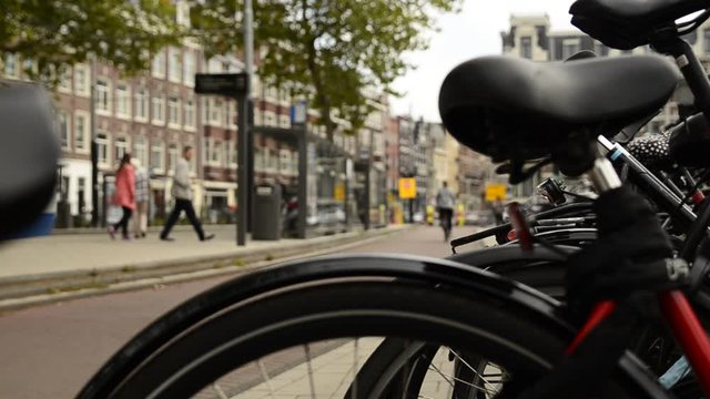 Amsterdam, Holland, August 2019.A particular point of view: from the blurred frame and saddle of a parked bike we see the cyclists passing on the cycle path. Change of focus .
