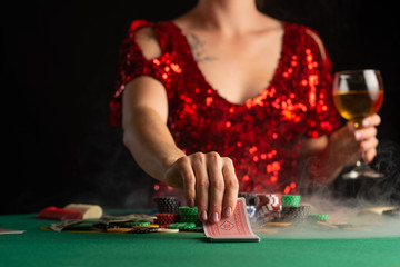 girl in evening dress plays poker in a casino. focus on the card and focus