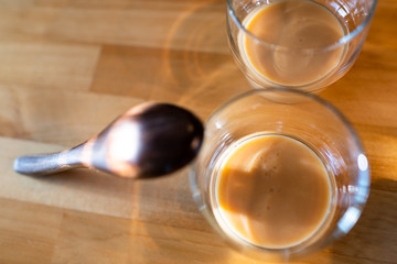 Flat top closeup view of two glasses with fermented Japanese traditional rice drink of amazake on kitchen wooden table with wood ladle spoon in Japan