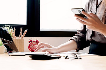 Close up female holding smartphone getting message with confirmation making transaction on laptop...