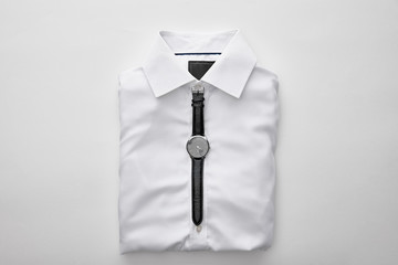 top view of watches on plain folded shirt on white background