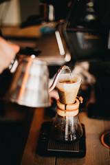 Fototapeta na wymiar Barista pouring coffee into glass chemex