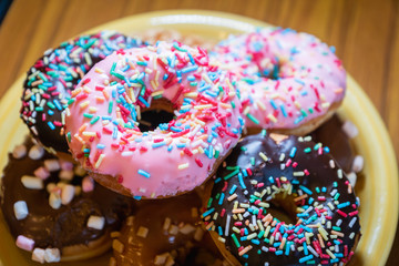  donuts, close-up photo with selective focus - assorted donuts with chocolate frosted, pink glazed and sugary sprinkles. 