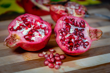 pomegranate fruit sliced on a wooden cutting board. Ripe pomegranate closeup with selective focus