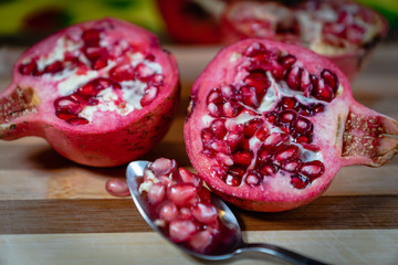 pomegranate fruit sliced on a wooden cutting board. Ripe pomegranate closeup with selective focus