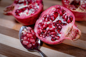 pomegranate fruit sliced on a wooden cutting board. Ripe pomegranate closeup with selective focus
