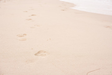 Adult foot print on sand and beach near sea water. Foot mark stepped on sea shore with sof sand