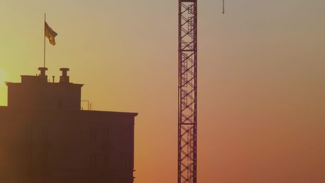 State torn flag of Ukraine on the building. A large national flag at dawn flutters in the wind near a construction crane. Ukrainian flag at sunset. 4k. 4k video. 60 fps