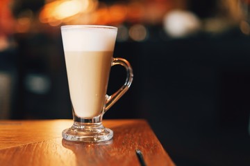 cup of coffee with cream on wooden background