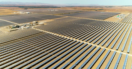 Solar panels in a solar farm in Spain. There is the reflection of the sun in the the panels which produce renewable energy, solar energy - aerial view with a drone - environment and renewable energy c