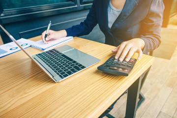 Business women are working with notebooks and calculators to calculate business profits.