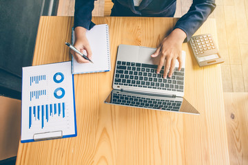 Business women are working with notebooks and calculators to calculate business profits.Top view
