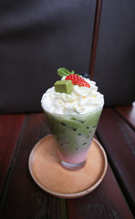Cold beverage, green tea smoothie with strawberry and blueburry and creamy on top with plastic straw in tall glass