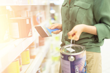 Woman shopping in hardware store. Girl is choosing paint in paint store. Banner with copy space