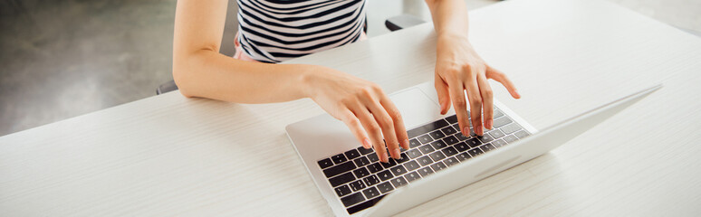 Fototapeta na wymiar panoramic shot of girl in striped t-shirt using laptop at home
