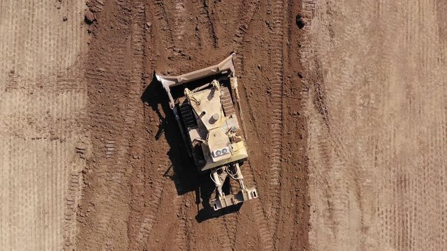 Bulldozer pushing large amount of fresh soil, Aerial follow footage.