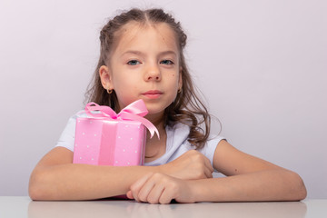 Smiling girl close-up on a gray background with a gift in her hands. Isolated-Image