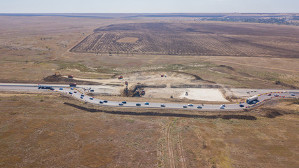 Aerial road constructions, machinery and mine equipment near road on sandy surface