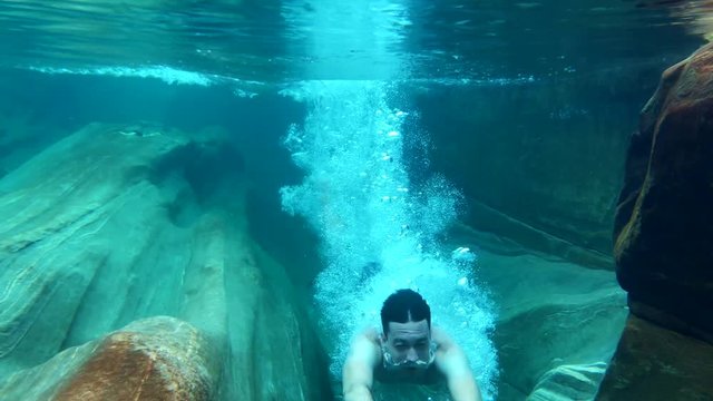 young man diving in water. epic underwater slow motion of a young man diving into crystal clear water in the nature outdoors. diving into the river in verzasca valley in lavertezzo switzerland.