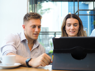 Smart man and woman using tablet and drinking coffee in cafe, lifestyle concept.