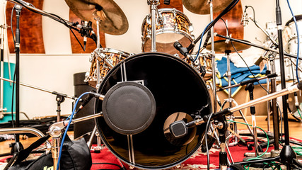 A front view of a drum kit set up for recording in a recording studio with microphones in place