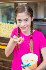Girl eating popcorn at a carnival or amusement park