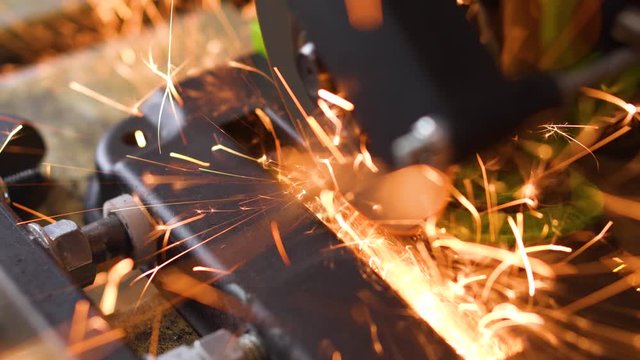 Angle grinder machine cuts tip off of screwdriver behind top view sparks fly
