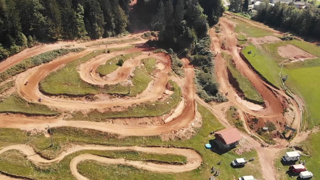 Motocross park review. Riders riding motorbikes on the track on a sunny day in summer. Drone shot.
