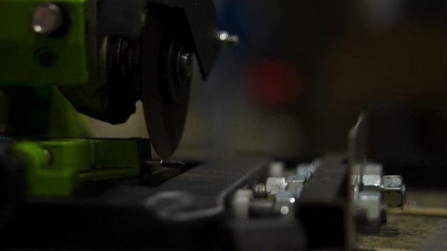 Angle grinding machine cutting tip of screwdriver producing sparks in slow motion low view