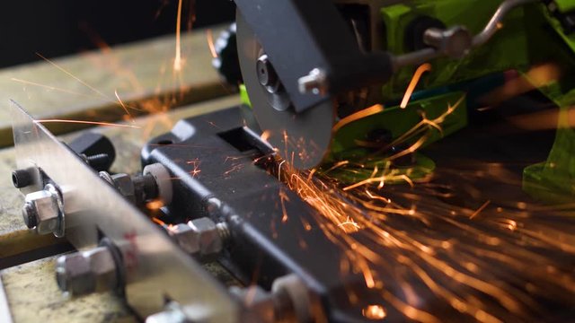 Angle grinder machine cuts tip off of screwdriver back side view sparks fly