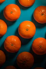 Bright tangerines on a darkened background in aquamarine. Double shadow. Selective focus. Top view. Low key lighting.
