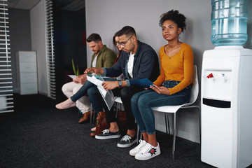 Young woman looking confident while sitting with a diverse group of job applicants in an office...
