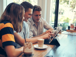 Fototapeta premium Smart man and woman using tablet and drinking coffee in cafe, lifestyle concept.