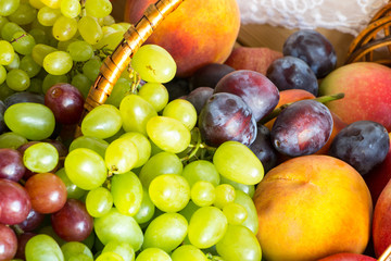 Close up heap of fresh fruits from new harvest poured out from wicker basket on wooden table.