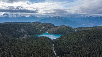Scenic aerial landscape view of a blue lake surrounded by mountains. Taken in Garibaldi, British Columbia, Canada
